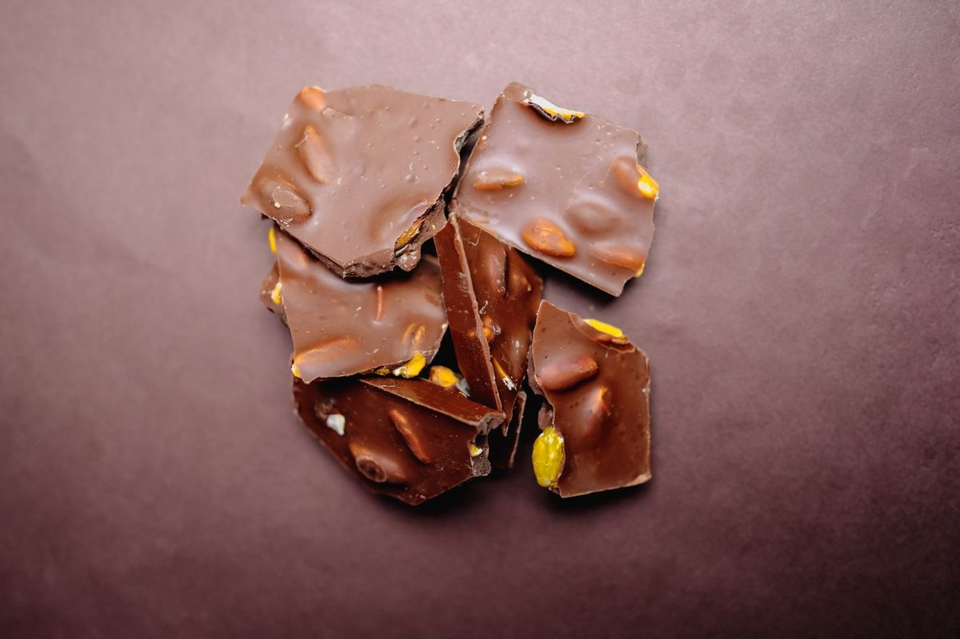Dark chocolate almond bark snapped into jagged shards on a dark board
